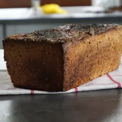 Bochenek ciemnego chleba żytniego z makiem na kuchennym blacie.