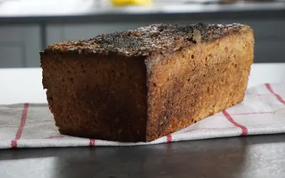 Bochenek ciemnego chleba żytniego z makiem na kuchennym blacie.