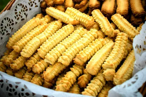 Koszyk pełen domowych, złocistych ciasteczek o charakterystycznym, karbowanym kształcie.