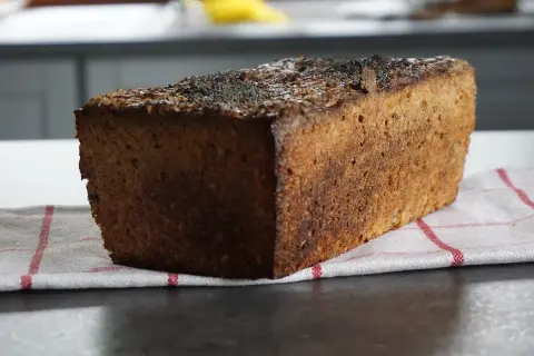 Bochenek ciemnego chleba żytniego z makiem na kuchennym blacie.