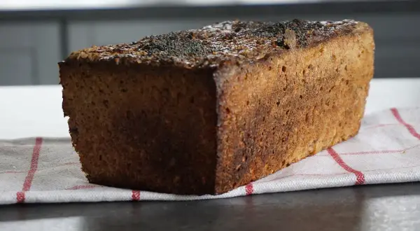 Bochenek ciemnego chleba żytniego z makiem na kuchennym blacie.